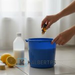Tangan seseorang menuangkan minyak atsiri ke dalam ember berisi campuran cuka dan air. Ilustrasi cara membuat pembersih lantai alami KALBERTPS.