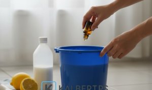 Tangan seseorang menuangkan minyak atsiri ke dalam ember berisi campuran cuka dan air. Ilustrasi cara membuat pembersih lantai alami KALBERTPS.