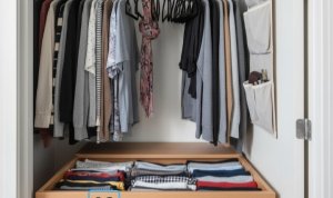 b106324c-55ad-4596-9bdd-4d1633d88380 Lemari pakaian kecil yang terorganisir rapi dengan lipatan vertikal KonMari dan gantungan beludru tipis. Tips optimalisasi ruang KALBERTPS.